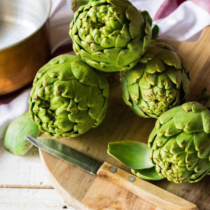 harvested artichokes on a cutting board in the kitchen